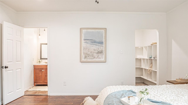 bedroom featuring sink, a spacious closet, crown molding, and wood-type flooring