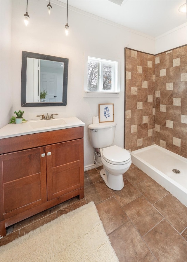 bathroom with toilet, tiled shower, vanity, and ornamental molding