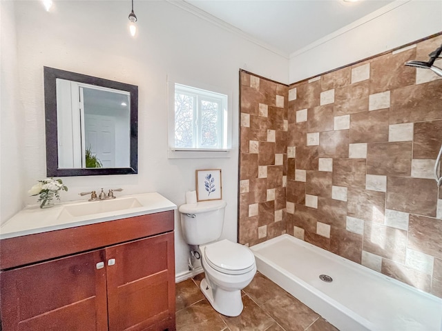 bathroom featuring vanity, tiled shower, toilet, tile patterned floors, and ornamental molding