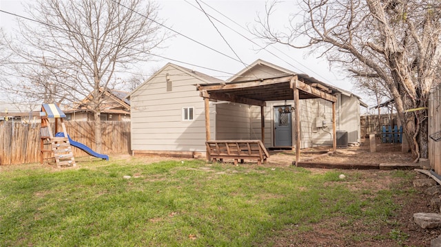 back of house with a playground, a yard, and central AC unit