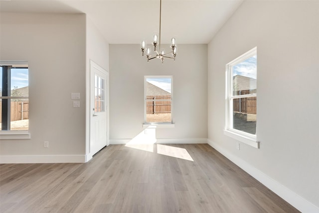 unfurnished dining area featuring light wood-type flooring and a notable chandelier