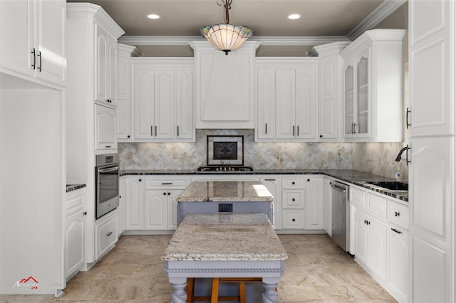 kitchen with stainless steel appliances, pendant lighting, a kitchen island, white cabinetry, and dark stone countertops