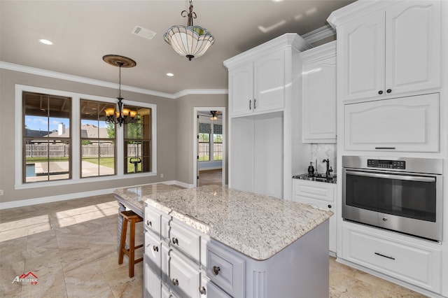 kitchen with stainless steel oven, white cabinetry, and decorative light fixtures