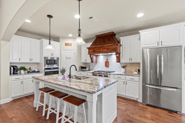 kitchen featuring white cabinets, appliances with stainless steel finishes, and custom range hood