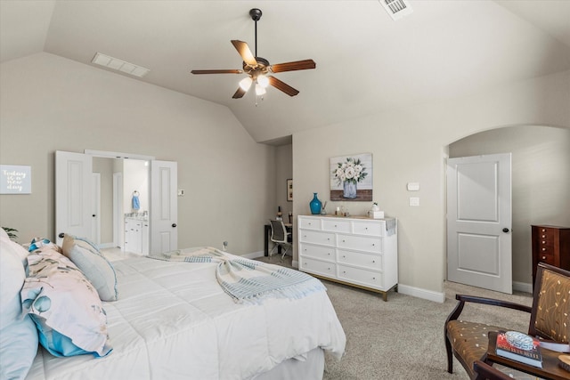 bedroom featuring vaulted ceiling, light colored carpet, ceiling fan, and ensuite bath