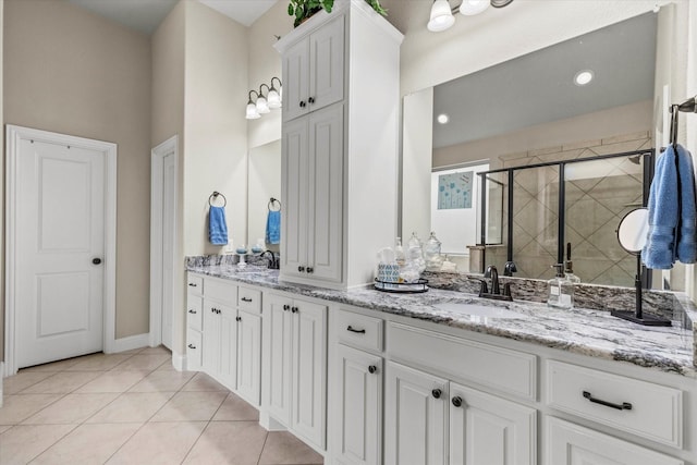 bathroom featuring a shower with shower door, vanity, and tile patterned floors