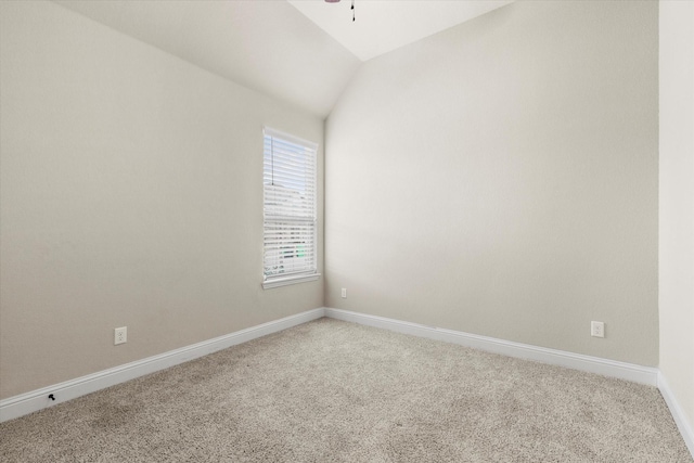 carpeted spare room featuring vaulted ceiling and ceiling fan