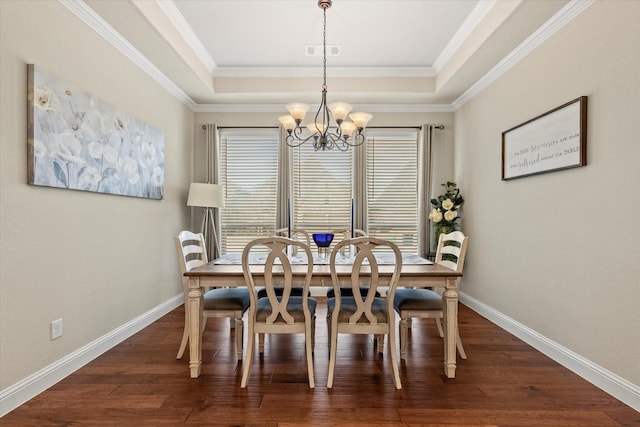 dining area with a tray ceiling, dark wood-type flooring, crown molding, and an inviting chandelier