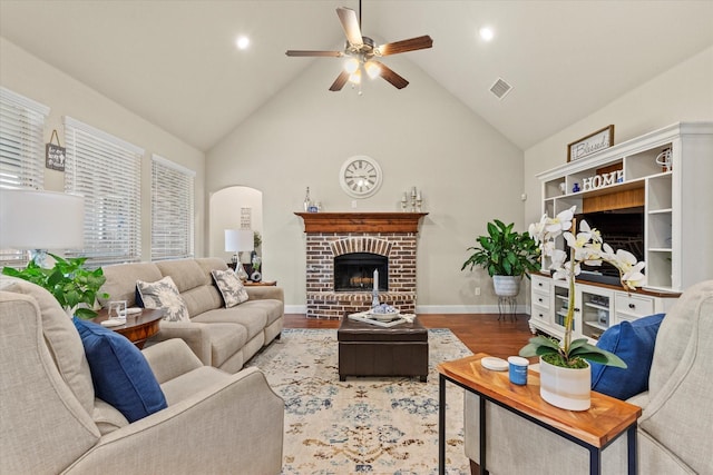 living room with a fireplace, hardwood / wood-style flooring, high vaulted ceiling, and ceiling fan