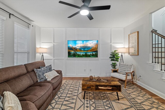 10012 Travis Dr, Providence Village, TX 76227 - living room featuring a decorative wall, wood finished floors, stairs, a ceiling fan, and baseboards