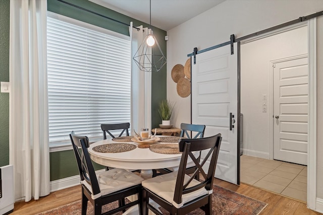 dining room with a barn door and light hardwood / wood-style floors