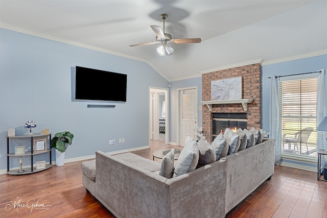 living room with a brick fireplace, vaulted ceiling, dark wood-type flooring, and ornamental molding