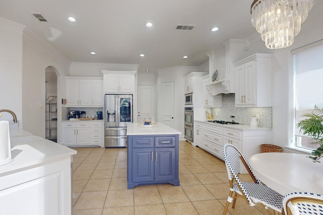 788 Windsong Ln, Rockwall, TX 75032 - kitchen featuring stainless steel appliances, white cabinetry, blue cabinetry, decorative backsplash, and crown molding