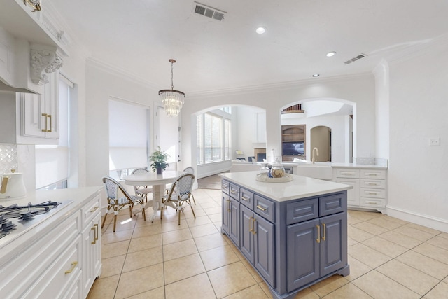 kitchen featuring light tile patterned floors, a notable chandelier, white cabinetry, a kitchen island, and decorative light fixtures