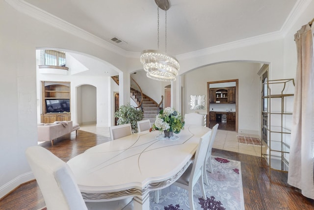 788 Windsong Ln, Rockwall, TX 75032 - dining area featuring arched walkways, ornamental molding, stairway, a chandelier, and wood finished floors