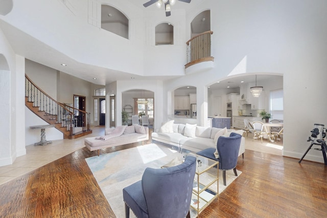 788 Windsong Ln, Rockwall, TX 75032 - living room featuring a towering ceiling, arched walkways, ceiling fan, stairway, and baseboards