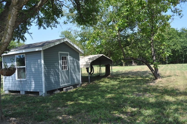 view of side of home featuring a lawn, a carport, and an outdoor structure