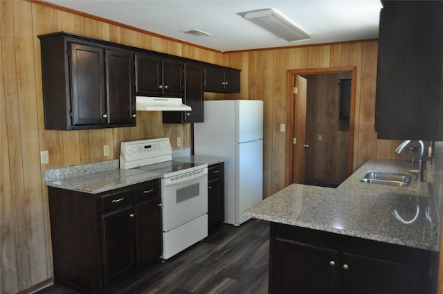 kitchen featuring dark hardwood / wood-style flooring, light stone countertops, sink, white appliances, and wooden walls