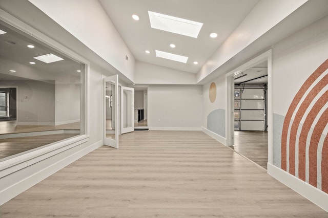 hall with vaulted ceiling with skylight and light hardwood / wood-style floors