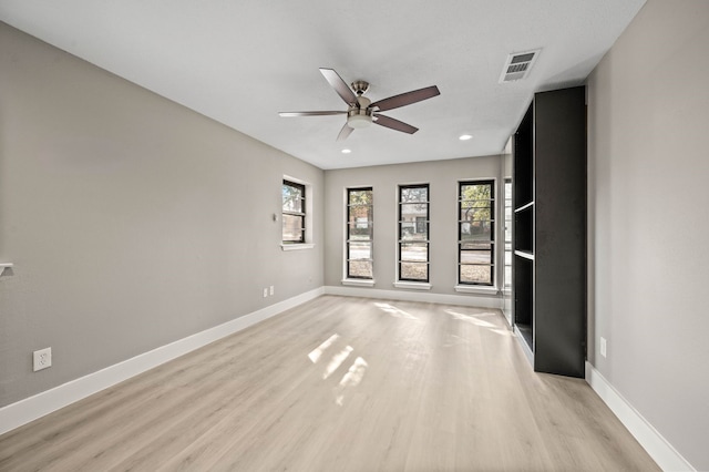 empty room with ceiling fan and light hardwood / wood-style flooring