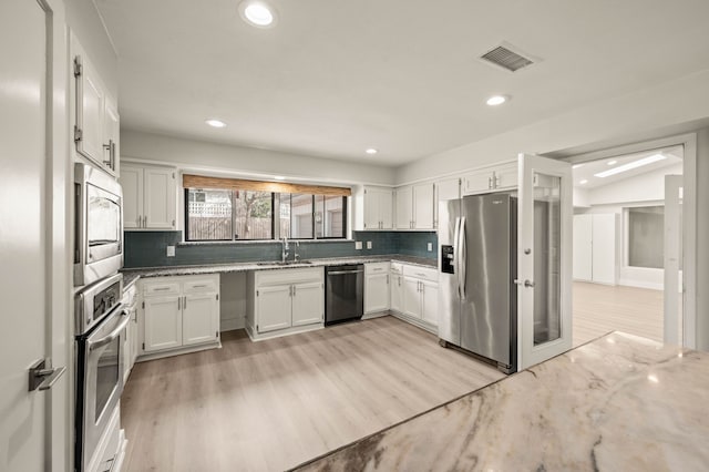 kitchen featuring white cabinetry, light stone countertops, sink, tasteful backsplash, and appliances with stainless steel finishes