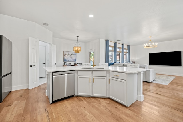 kitchen with a center island with sink, appliances with stainless steel finishes, a chandelier, and white cabinets