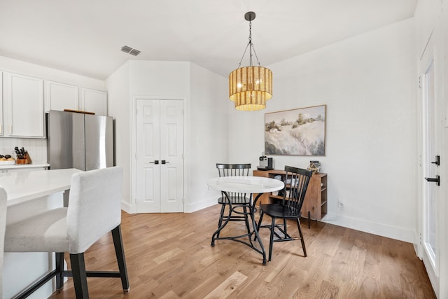 dining space featuring light wood-type flooring and an inviting chandelier