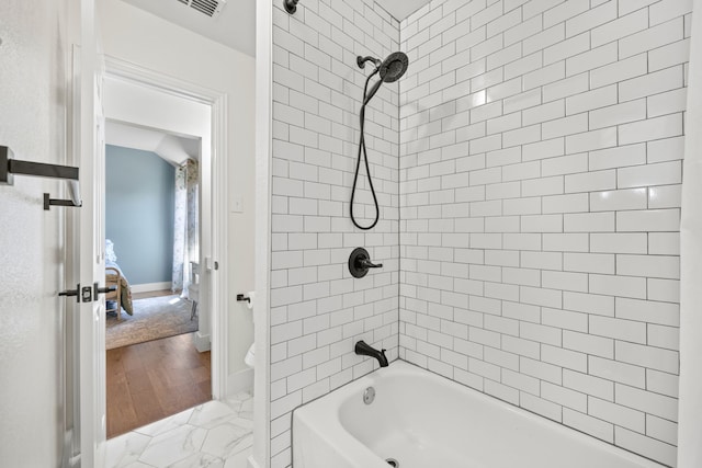 bathroom featuring lofted ceiling and tiled shower / bath