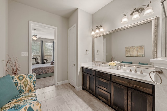 ensuite bathroom with double vanity, ensuite bath, a sink, and baseboards