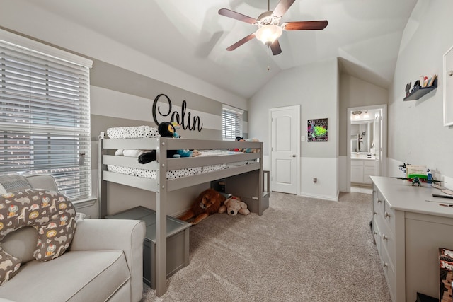 bedroom with vaulted ceiling, light carpet, ensuite bath, and a ceiling fan