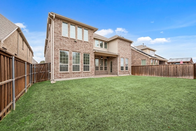 back of house with a fenced backyard, brick siding, and a lawn