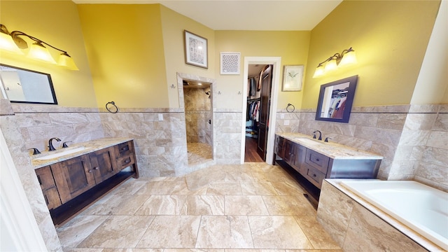 bathroom with tile walls, vanity, and independent shower and bath