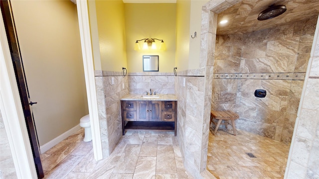 bathroom with tile walls, vanity, tiled shower, and toilet