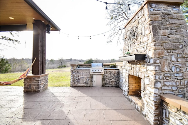 view of patio featuring an outdoor stone fireplace, an outdoor kitchen, and a grill