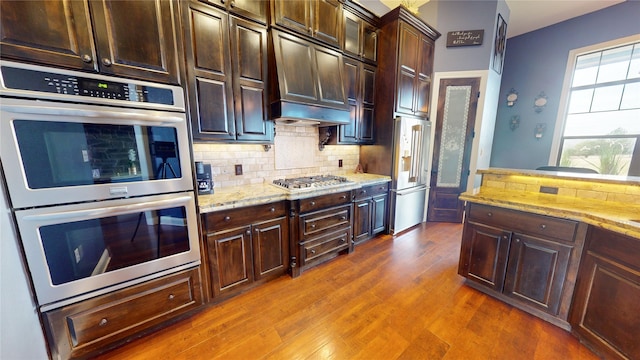 kitchen featuring light stone countertops, dark wood-type flooring, stainless steel appliances, and tasteful backsplash