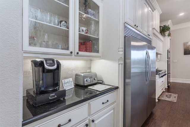 kitchen with dark wood-style flooring, tasteful backsplash, ornamental molding, white cabinetry, and built in appliances