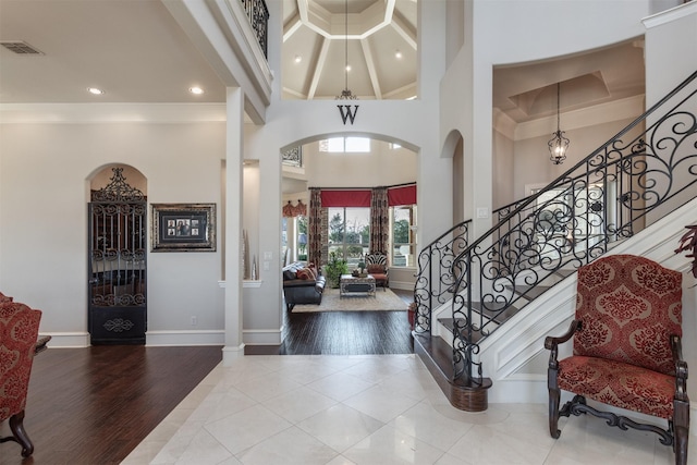 entryway featuring a high ceiling, visible vents, wood finished floors, and ornamental molding