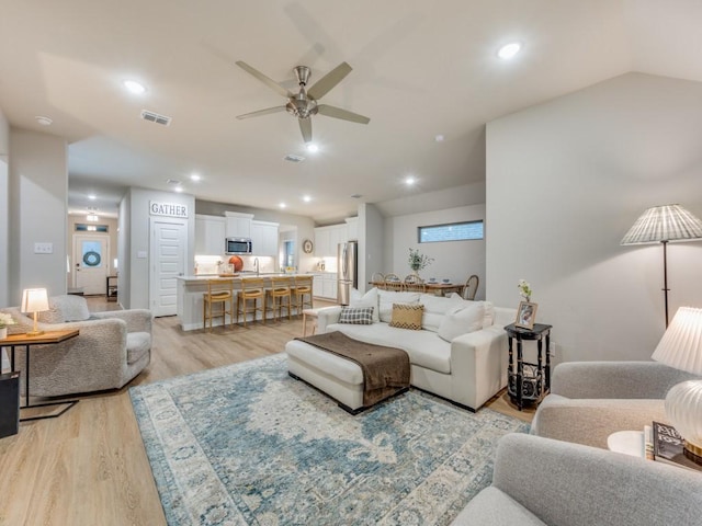 living room featuring light hardwood / wood-style floors, ceiling fan, and sink