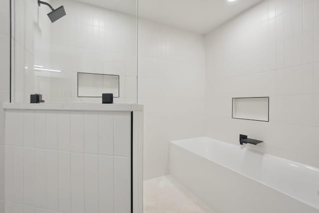 bathroom featuring plus walk in shower and tile walls