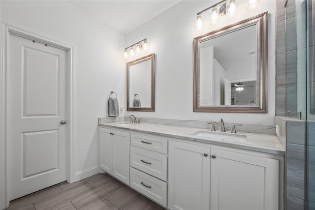 bathroom featuring double vanity, wood finish floors, a sink, and baseboards