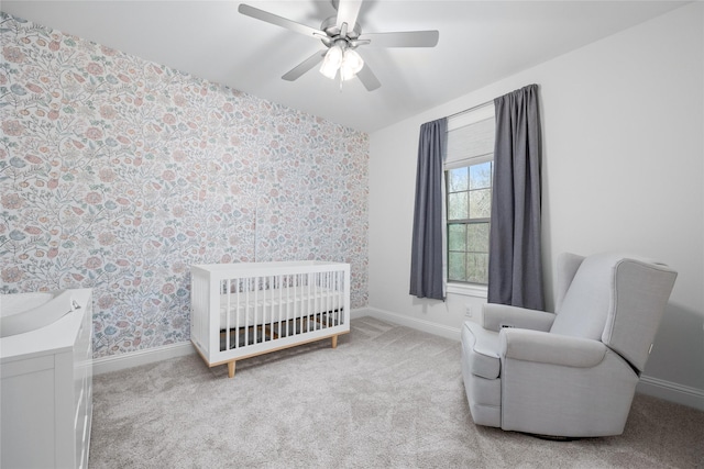 bedroom featuring a nursery area, baseboards, light carpet, and wallpapered walls