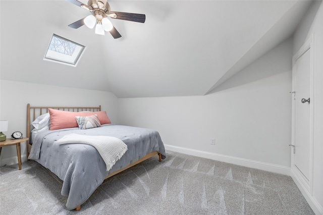 bedroom with a ceiling fan, baseboards, lofted ceiling with skylight, and carpet flooring