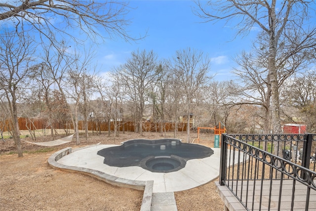 view of yard with a hot tub, fence, and a playground