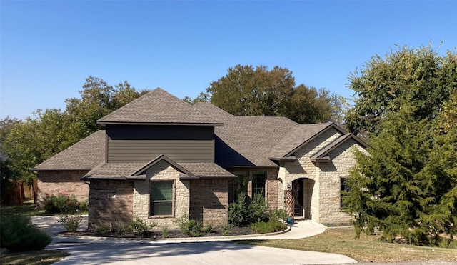 view of front of property with stone siding, brick siding, and roof with shingles