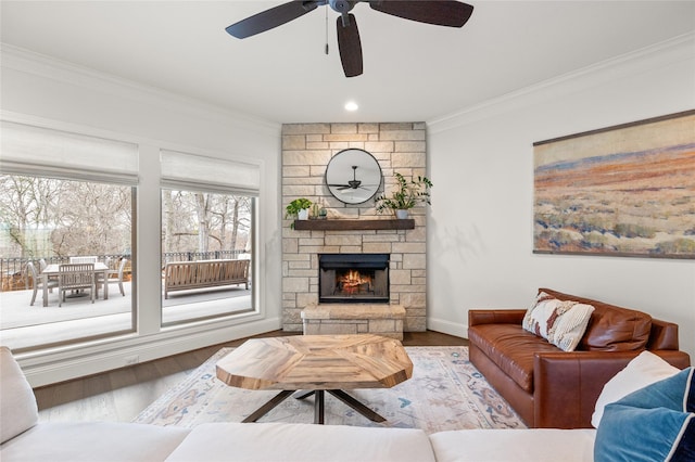 living room with light wood finished floors, ornamental molding, a fireplace, and baseboards