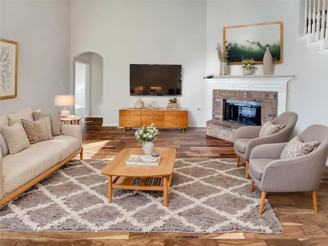 living room featuring dark wood-type flooring, a high ceiling, and a fireplace