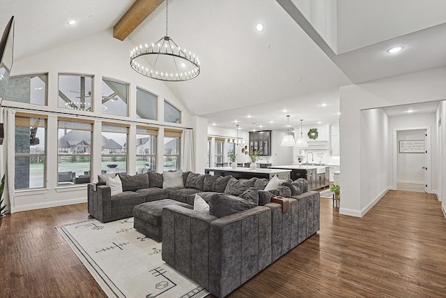 living room with sink, a notable chandelier, beamed ceiling, dark wood-type flooring, and high vaulted ceiling