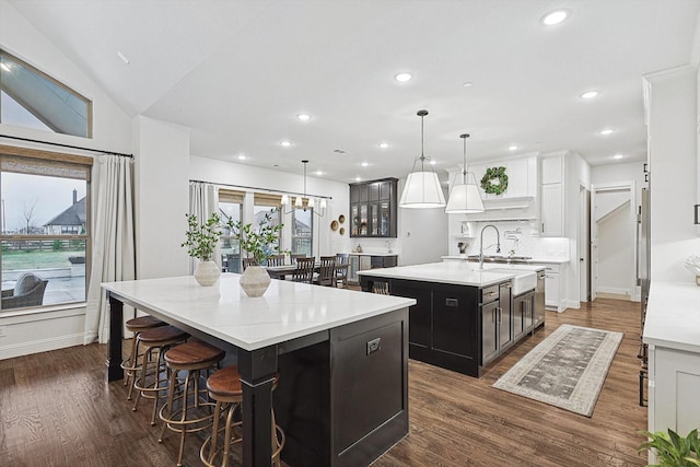 kitchen featuring a large island, hanging light fixtures, sink, dark wood-type flooring, and white cabinets