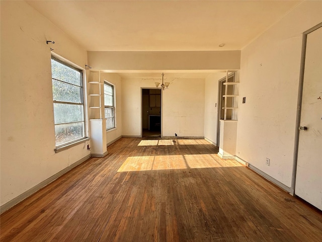 unfurnished room with baseboards, a chandelier, and wood finished floors