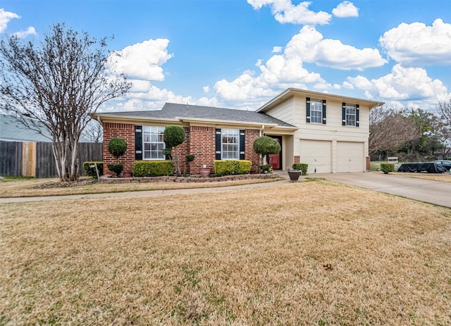 tri-level home with fence, concrete driveway, a front lawn, a garage, and brick siding